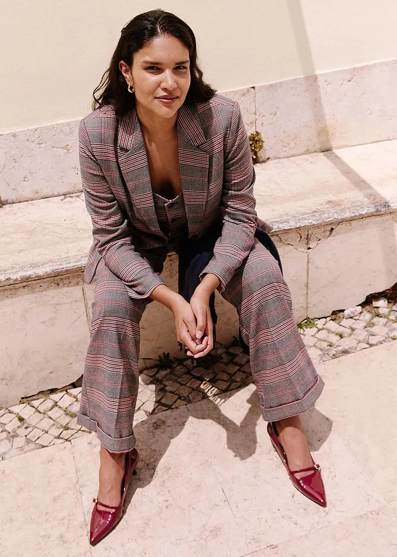 Geruite blazer en een bijpassende broek gecombineerd met rode schoenen.