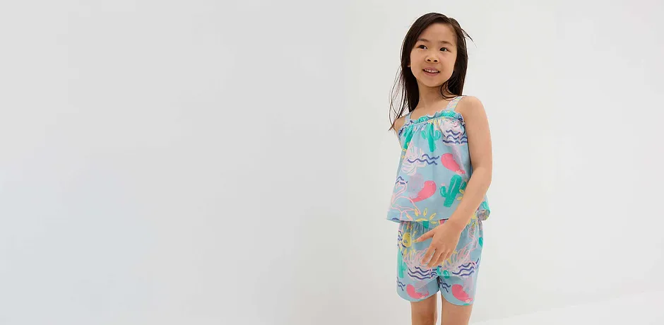 Sommerliches Outfit mit pastellfarbenem Top und kurzer Hose, verziert mit Flamingo- und Kaktusmotiven.