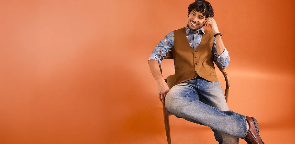 Stijlvolle combinatie van jeans, een overhemd met print en een bruin gilet.