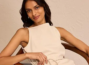 Elegante, cremekleurige jurk met hoge halslijn. Riem benadrukt slank silhouet.