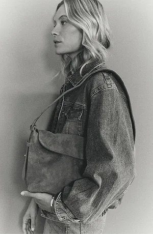 Een klassieke jeansjack met studs, gecombineerd met een eenvoudige leren tas voor een casual look.