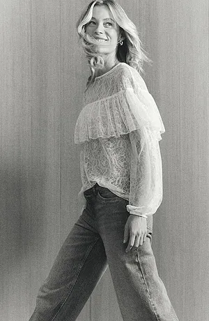 Romantische witte kanten blouse met ruches, gecombineerd met klassieke jeans voor een casual-elegante look.