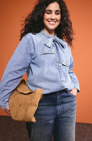 Lichtblauwe jeansblouse met strikkragen, donkere jeans en een bruine leren tas voor een casual dagelijkse look.