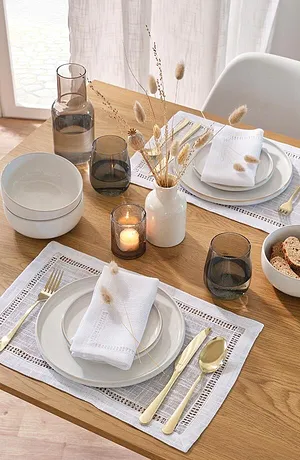Elegante tafellaken met kantpatroon, witte stoffen servetten en gouden bestek zorgen voor stijlvolle accenten.
