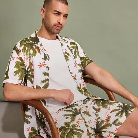 Tropisch shirt en shorts met palmenpatroon, daaronder een eenvoudig wit T-shirt.