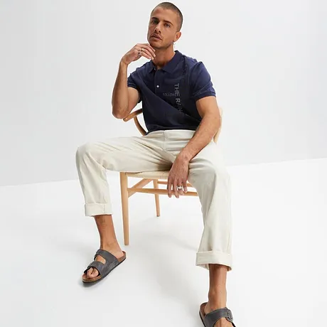 Donkerblauw poloshirt met witte broek en grijze sandalen. Casual zomerlook voor de dagelijkse outfit.