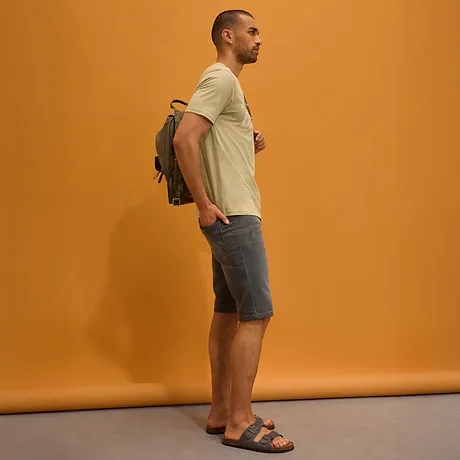 Licht T-shirt, grijze jeans short, sandalen en een rugzak