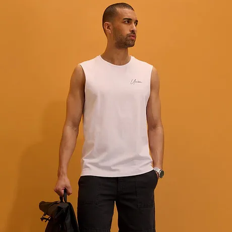 Wit mouwloos shirt, donkere short, witte sneakers en een zwarte rugzak.