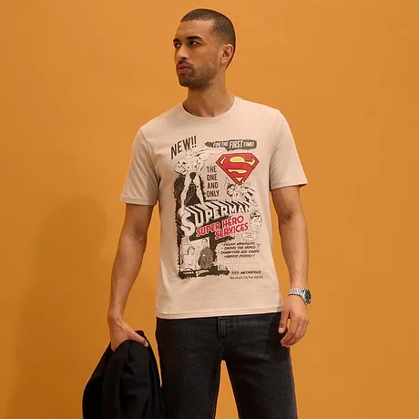 Een wit T-shirt met Superman, korte donkere broek en sandalen.