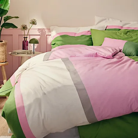 Vrolijke dekbedovertrekken in roze, wit en groen zorgen voor een aangename sfeer in de slaapkamer.