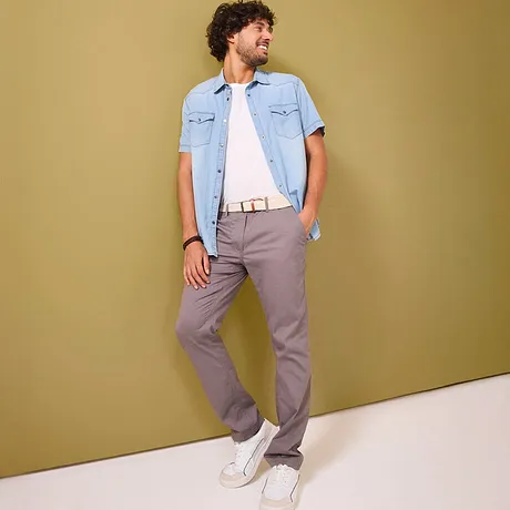 Grijze chino broek gecombineerd met een lichtblauw jeanshemd.