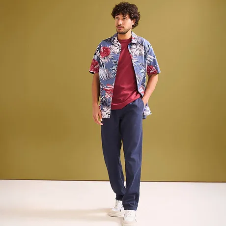 Kleurrijk Hawaiihemd over een rood T-shirt en donkere broek.
