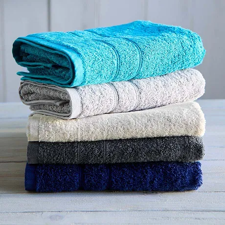 Een stapel zachte handdoeken in verschillende kleuren: turquoise, wit, beige, donkergrijs en marineblauw.