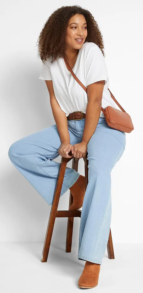 Wit T-shirt met wijde hals, lichte jeans en een bruine leren tas.