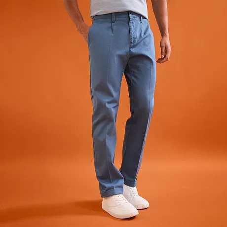 Casual lichtblauwe chino-broek met witte sneakers.