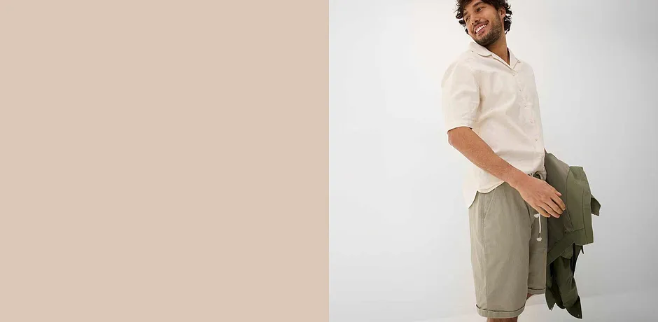 Luchtig wit overhemd met kraag, beige shorts en een groene jas voor een ontspannen zomerlook.