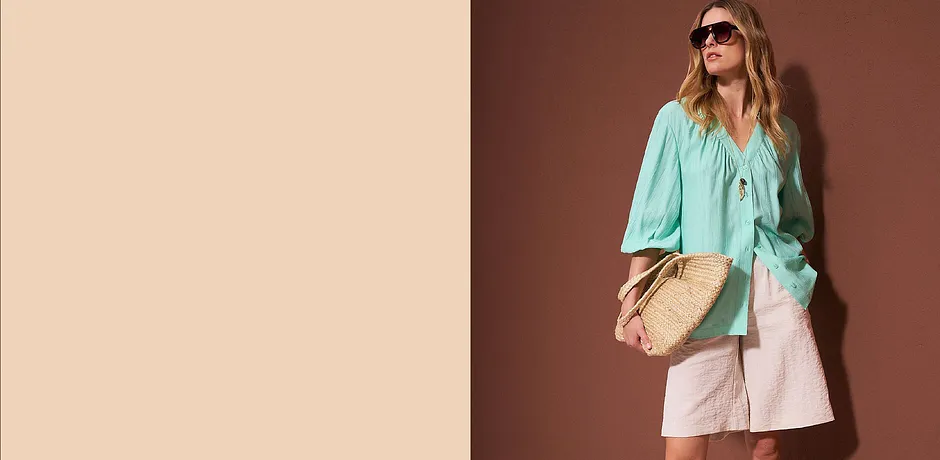 Türkisfarbene Bluse, helle Shorts und Strohhandtasche