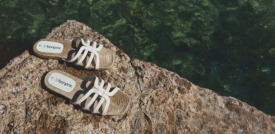 Witte sandalen op een rotsachtige ondergrond aan het strand.