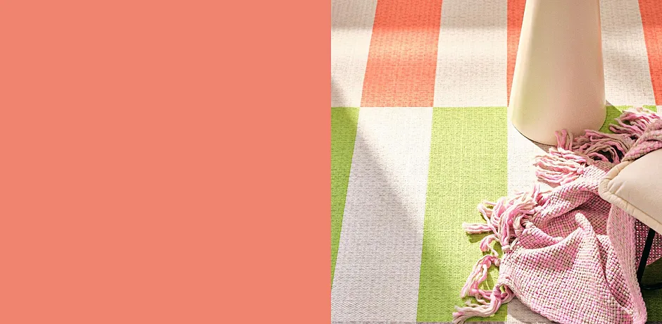 Gestreept vloerkleed in vrolijke kleuren met een roze knuffeldeken en een moderne bijzettafel.