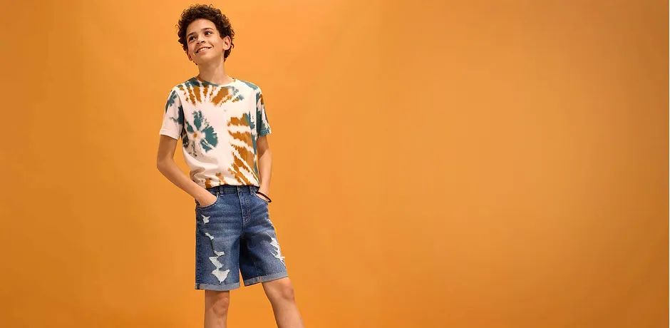 Sommerliches Outfit mit buntem Hemd und zerrissener Jeans-Shorts.