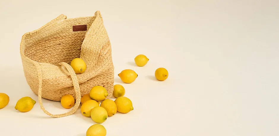 Geweven rieten tas met hengsels, gevuld met verse citroenen.