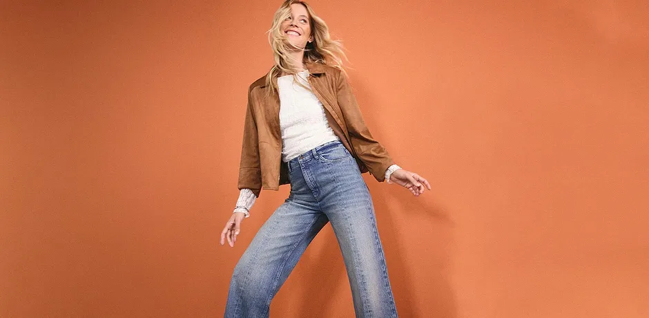 Casual look: Bruine leren jack, wit topje en wijde jeans voor een ontspannen stijl.