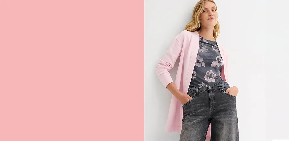 Lange roze vest op donkere jeans. Elegante contrast tussen lichte en donkere kleurtinten.