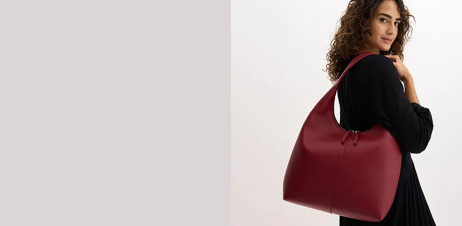 Elegante zwarte trui gecombineerd met een opvallende bordeauxrode handtas.