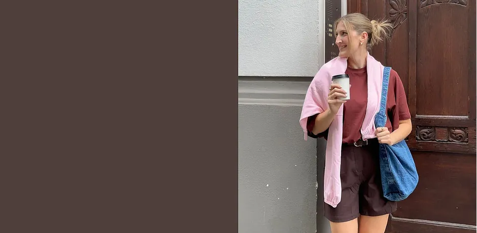 Zomerse outfit met een roze vest, bruine shorts en een blauwe tas.