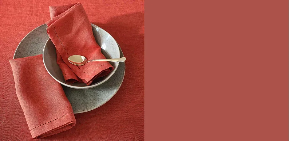 Tafeldecoratie in knalrood: servetten op grijze borden met gouden bestek.