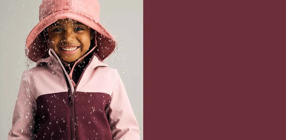 Regenjas in roze en bordeaux gecombineerd met een regenhoed. Perfect voor slecht weer.